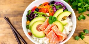 Reis-Bowl mit Avocado und Lachs auf einem Tisch.