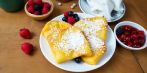 Schüssel mit Grießschmarren, Beeren und Puderzucker.