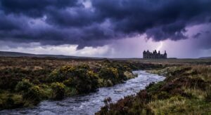 Eine stürmische Moorlandschaft mit dunklen Wolken und einem alten Herrenhaus im Hintergrund
