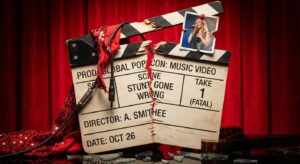 Symbolische Filmklappe vor rotem Hintergrund, die eine dramatische Promi-Stunt-Verletzung andeutet