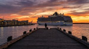 Kreuzfahrtschiff verlässt den Hafen bei Sonnenuntergang, Pier im Vordergrund