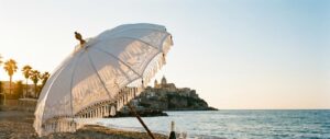 Eleganter Hochzeitsschirm vor sizilianischer Meerkulisse bei Sonnenuntergang – symbolisch für glamouröse Promi-Hochzeit