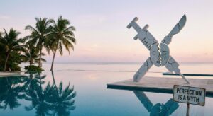 Symbolisches Bild: tropische Urlaubsszenerie mit zerbrochenem Beauty-OP-Symbol – ironisch und ohne Personen
